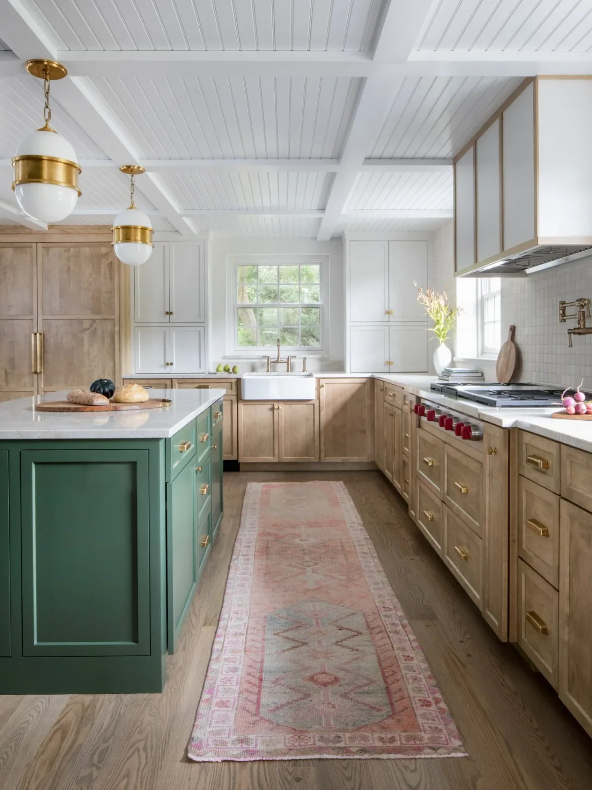 A green island stands among natural wood lower cupboards and white upper cabinets beneath a white paneled kitchen ceiling.