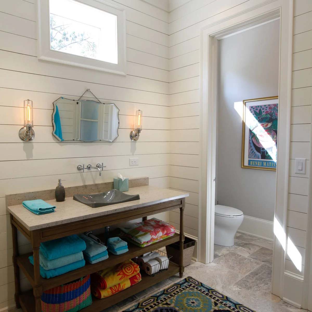 Open washstand shelves with turquoise towels, baskets and spare toilet paper