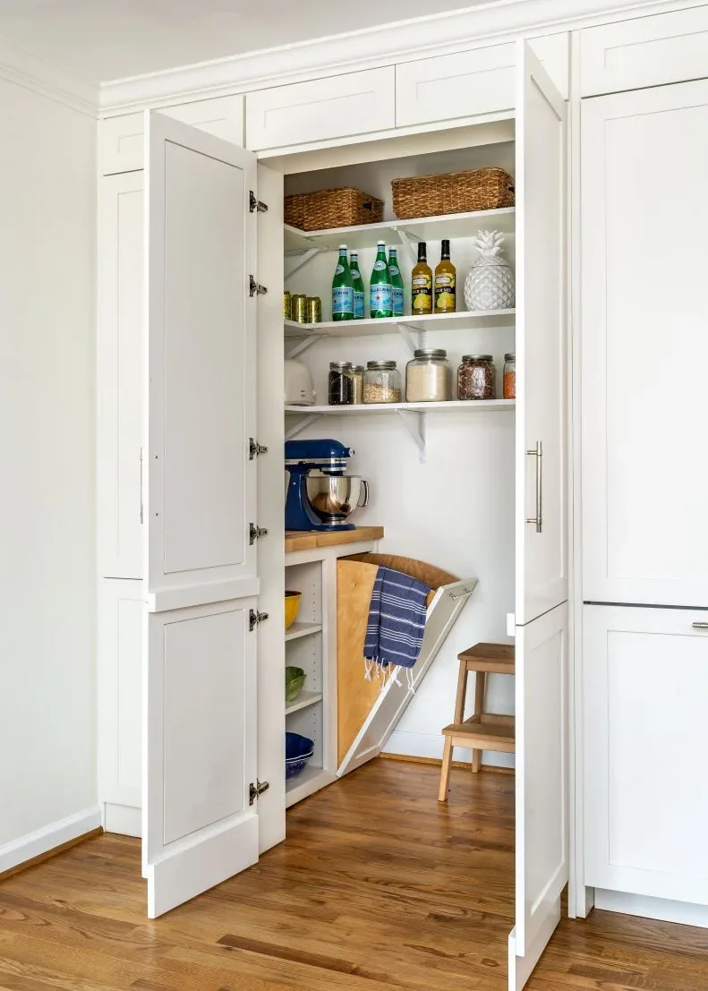 White paneled pantry entrance with baskets, jars, mixer station and small wood step stool