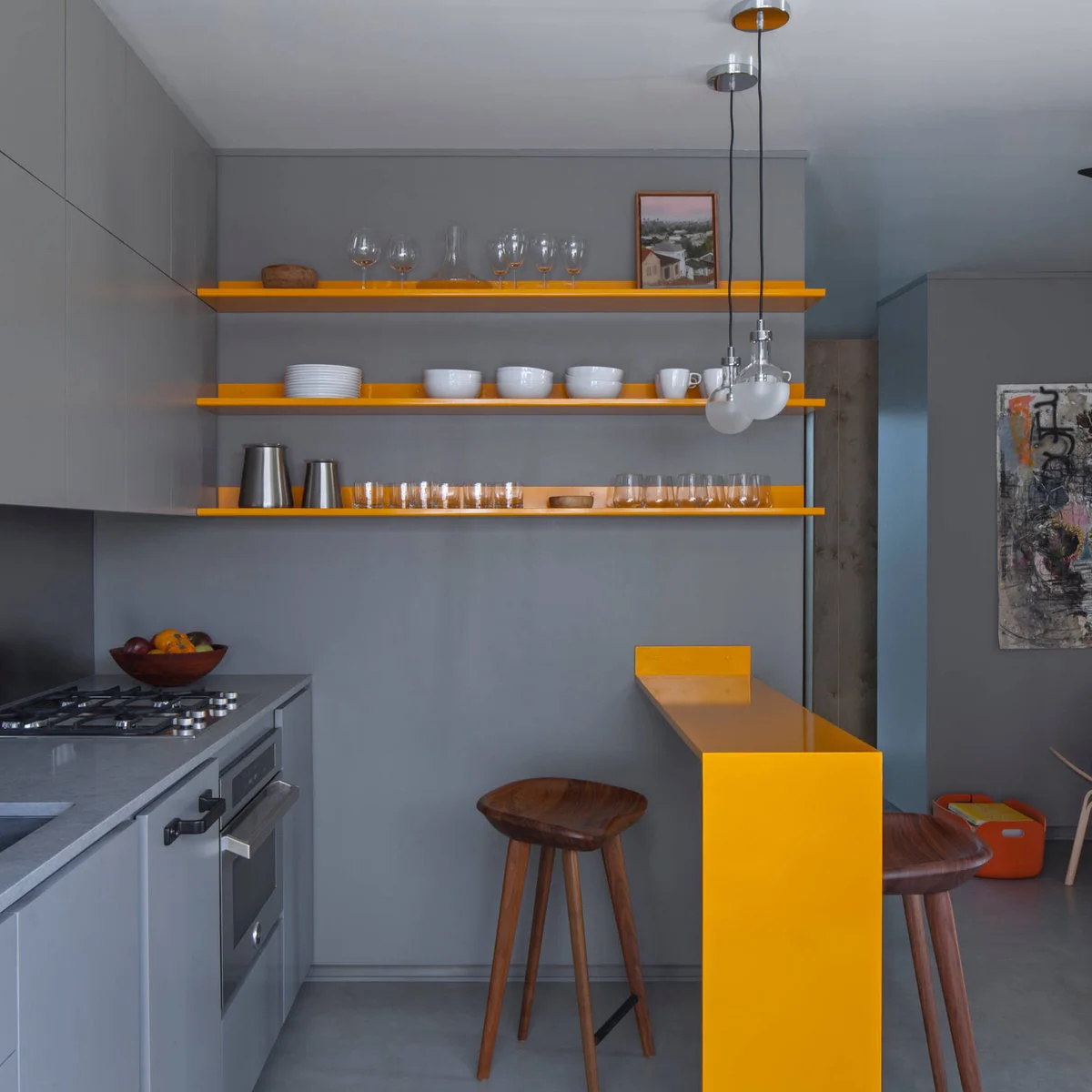 Gray kitchen with yellow open shelves and a narrow yellow breakfast ledge