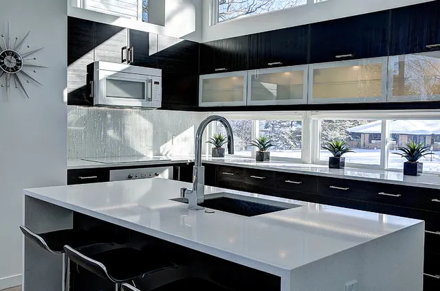 Dark upper cabinets include translucent panels above a bright window and pale island.