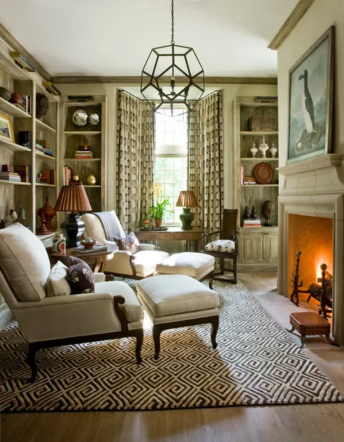 A pale chair and footstool sit near a fireplace beneath a pendant.
