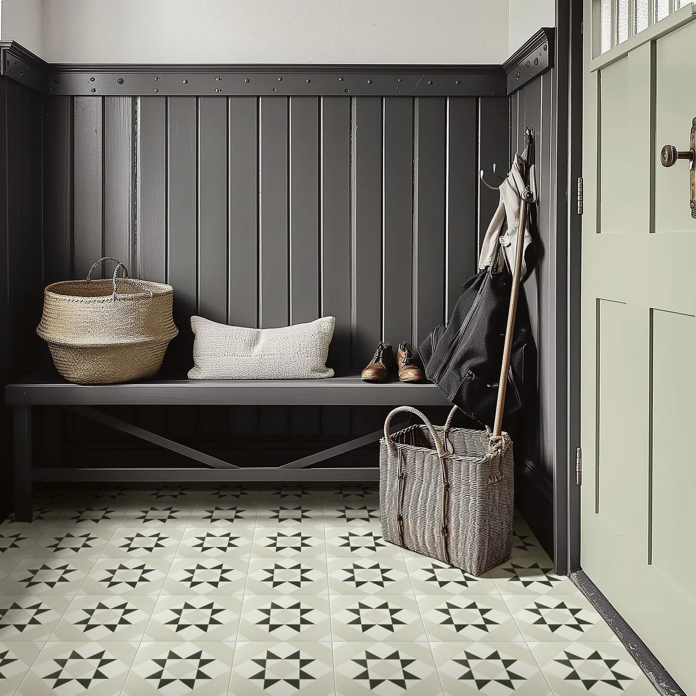 Entrance corner with dark gray vertical paneling, matching bench, woven baskets, hooks, pale cushion and patterned tiled floor.