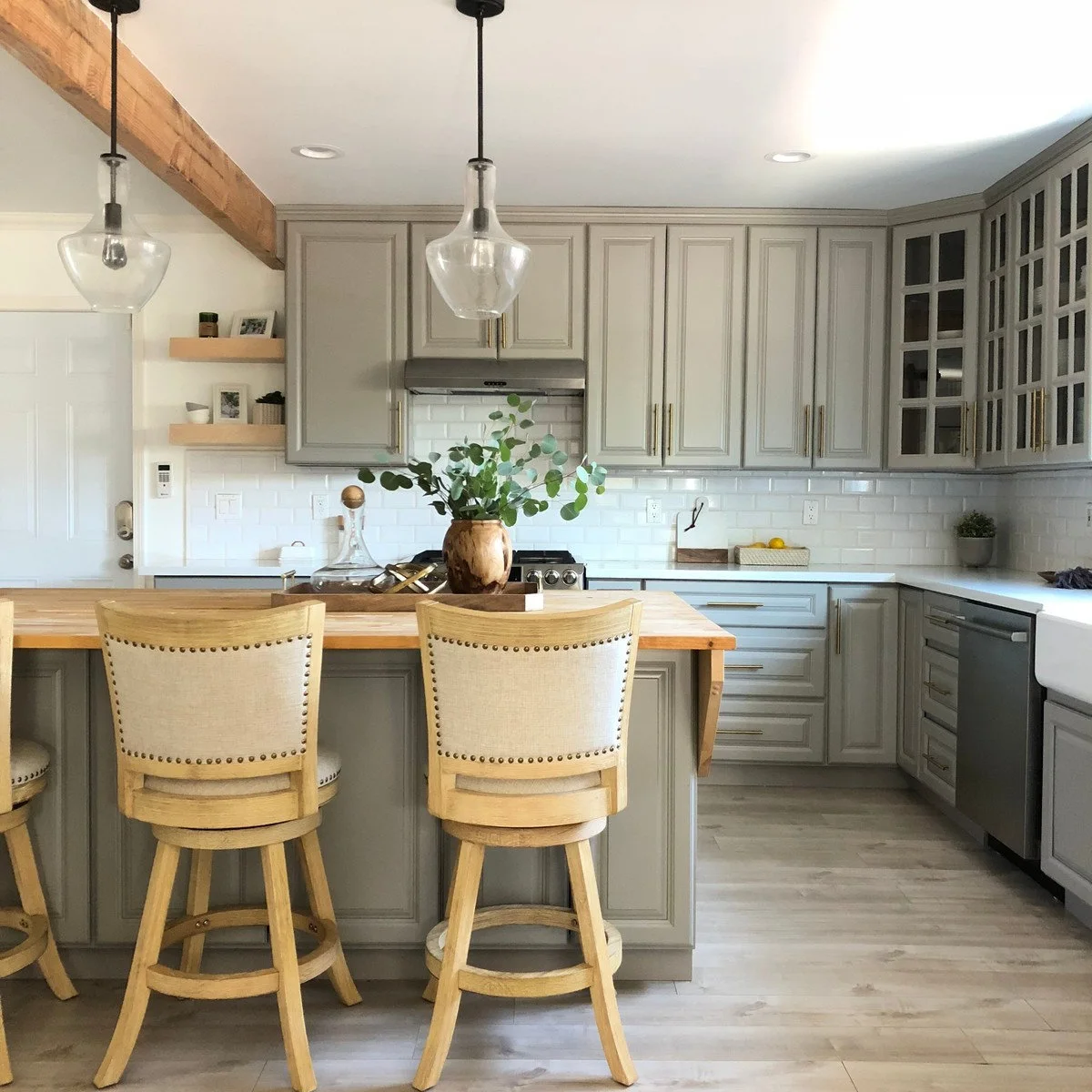 Gray kitchen with a wooden island top and glass-fronted upper corner cabinets