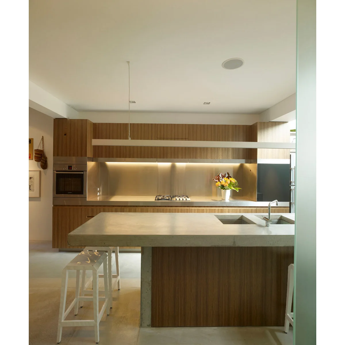 Wood-colored terraced-house kitchen with a pale island counter and two white stools