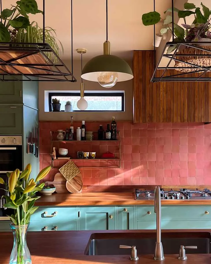 Close-up of blush handmade-look backsplash tile, wooden slat extractor housing and open kitchen shelves