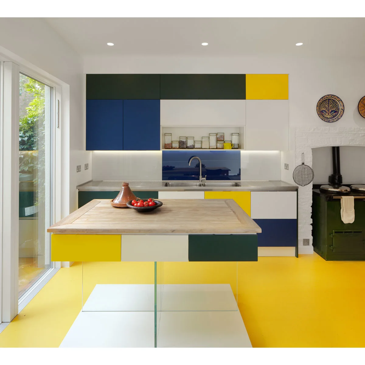 Color-block kitchen with yellow flooring and cabinet panels among blue, green and white sections