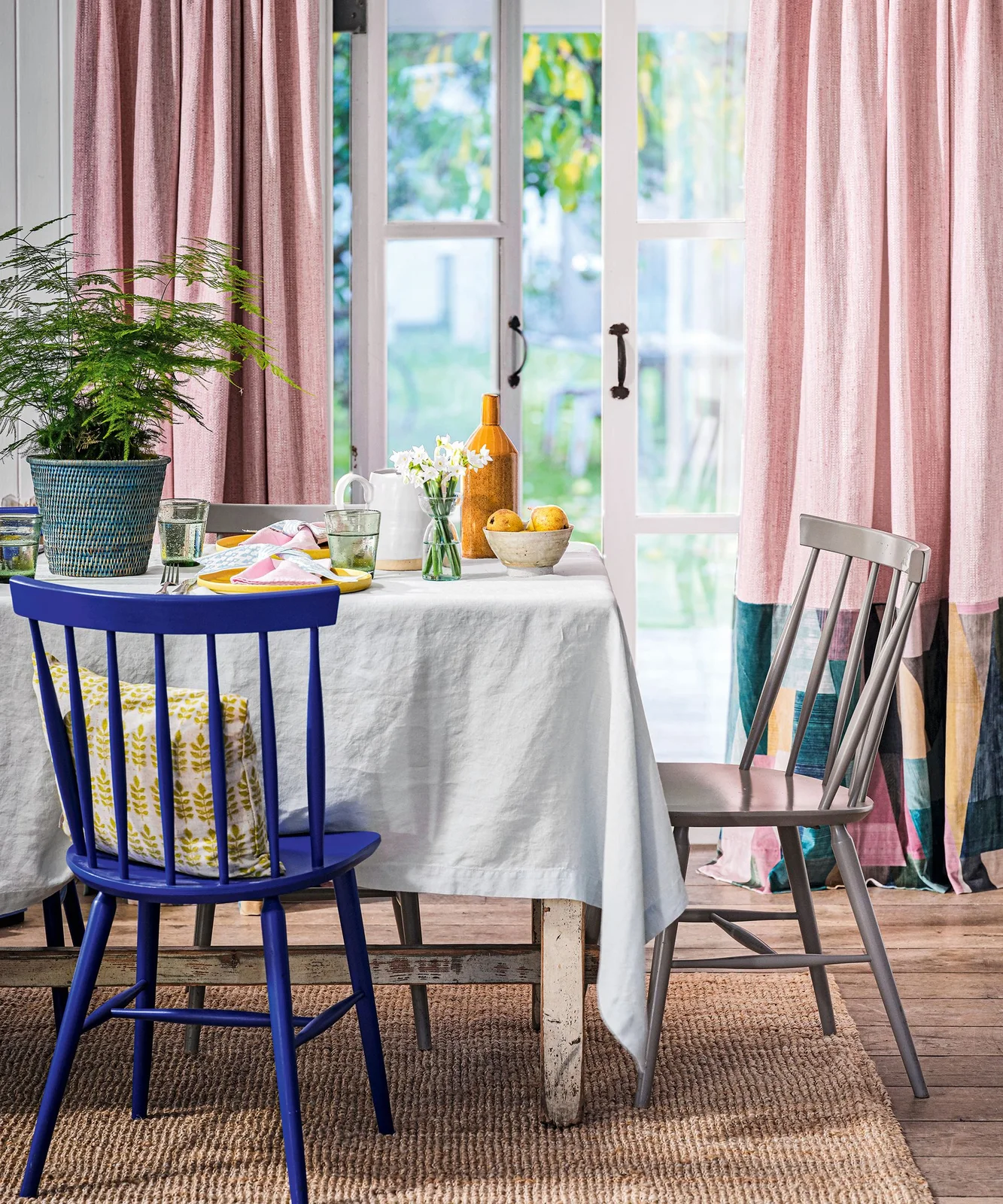 Pink curtains with dark teal lower sections beside a glass dining table