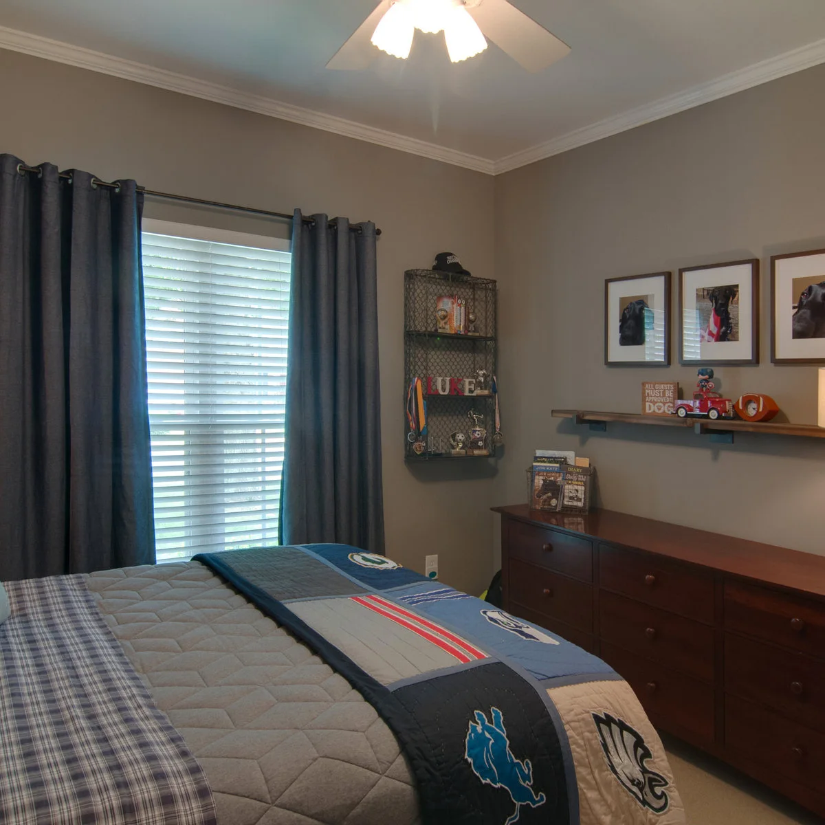 Teen bedroom with framed dog photographs, a wood-colored dresser and a narrow display ledge