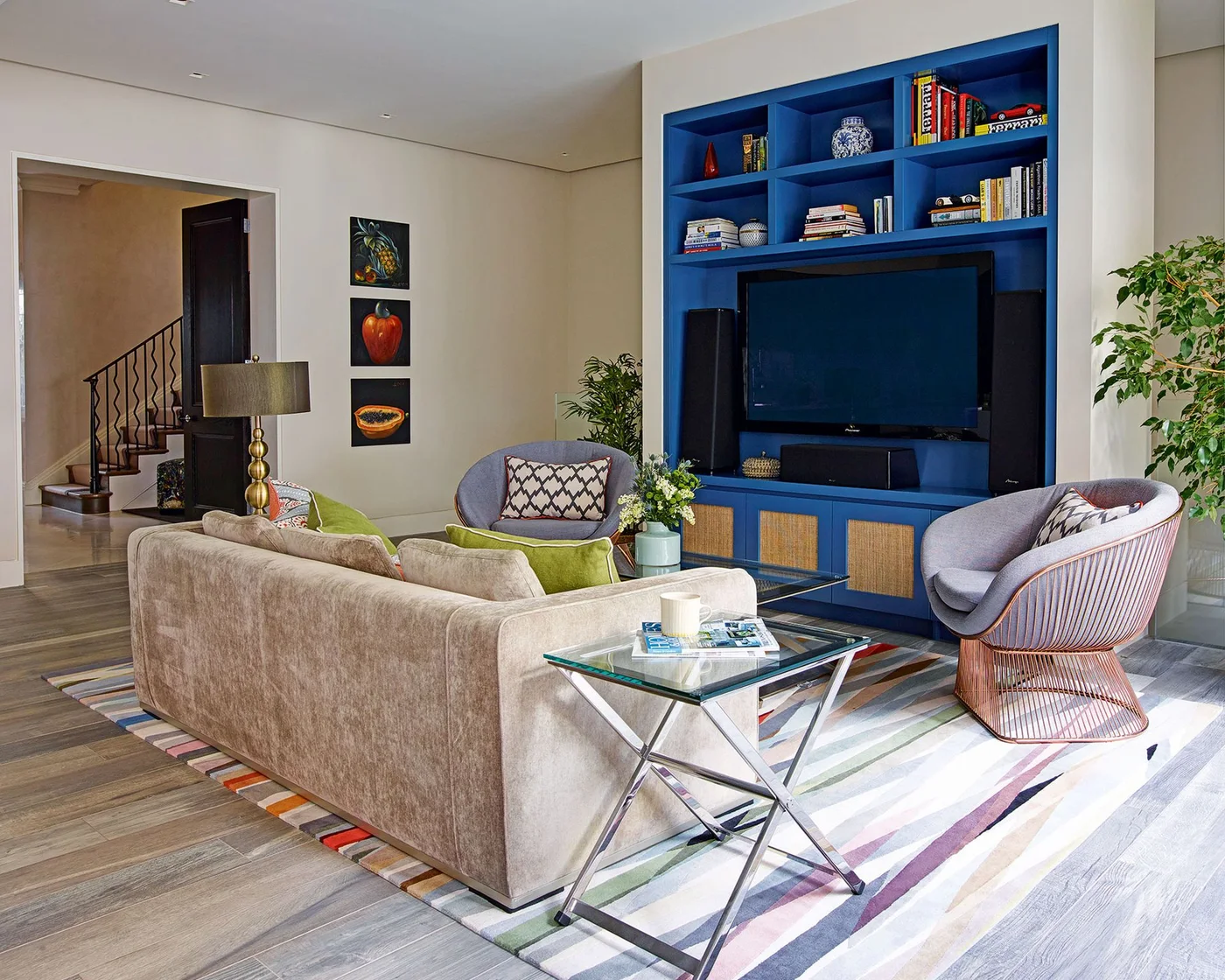 Blue floor-to-ceiling media cabinet with books above the TV and woven panels below