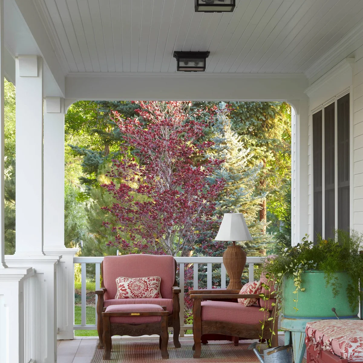 White boarded porch ceiling with simple dark lights above red upholstered chairs