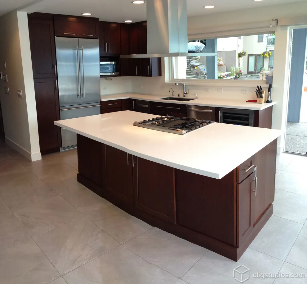 A deep brown wood island with a white worktop faces a bright perimeter counter