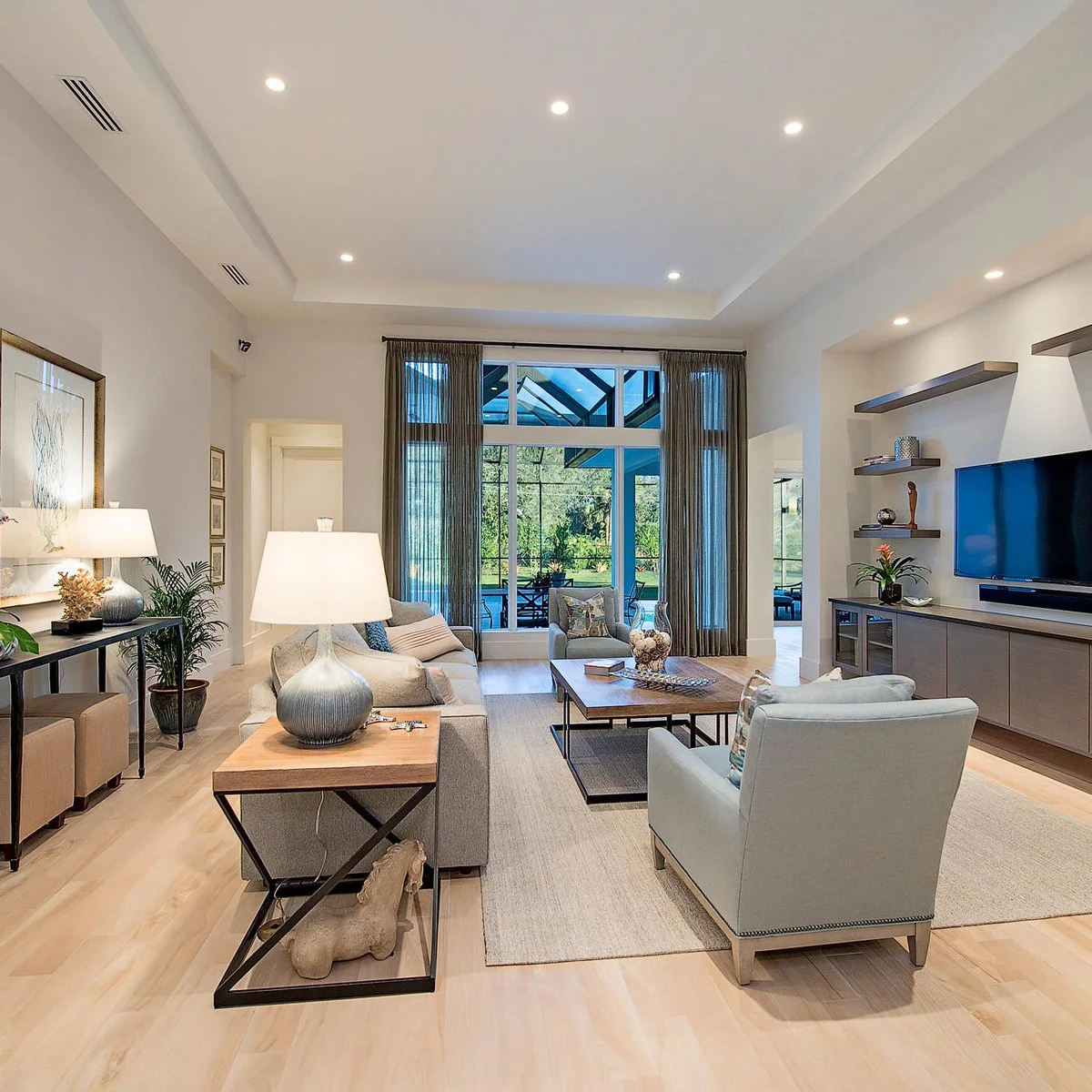 A pale sofa floats opposite a television wall, with two armchairs at the ends of a rectangular coffee table.