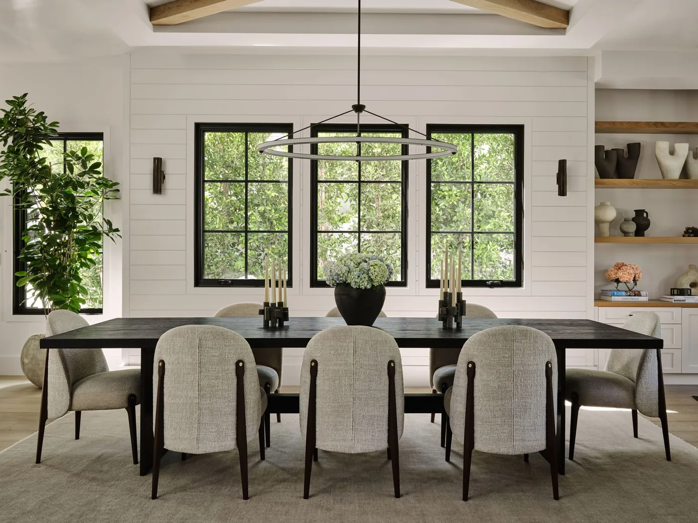 Open ring pendant above a dark table with two small dark wall lights beside black-framed windows
