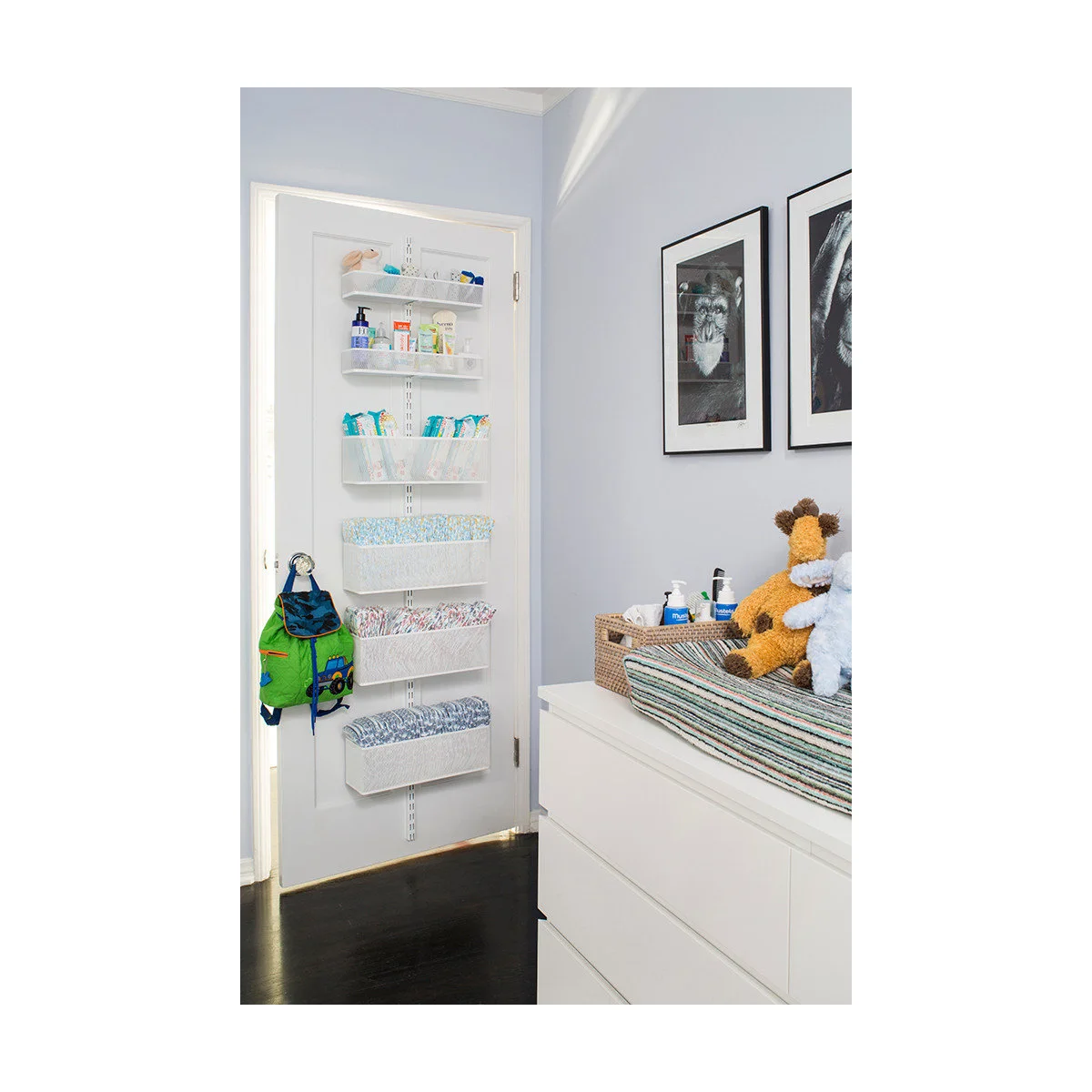 White door with narrow wire baskets for nursery supplies beside a white dresser