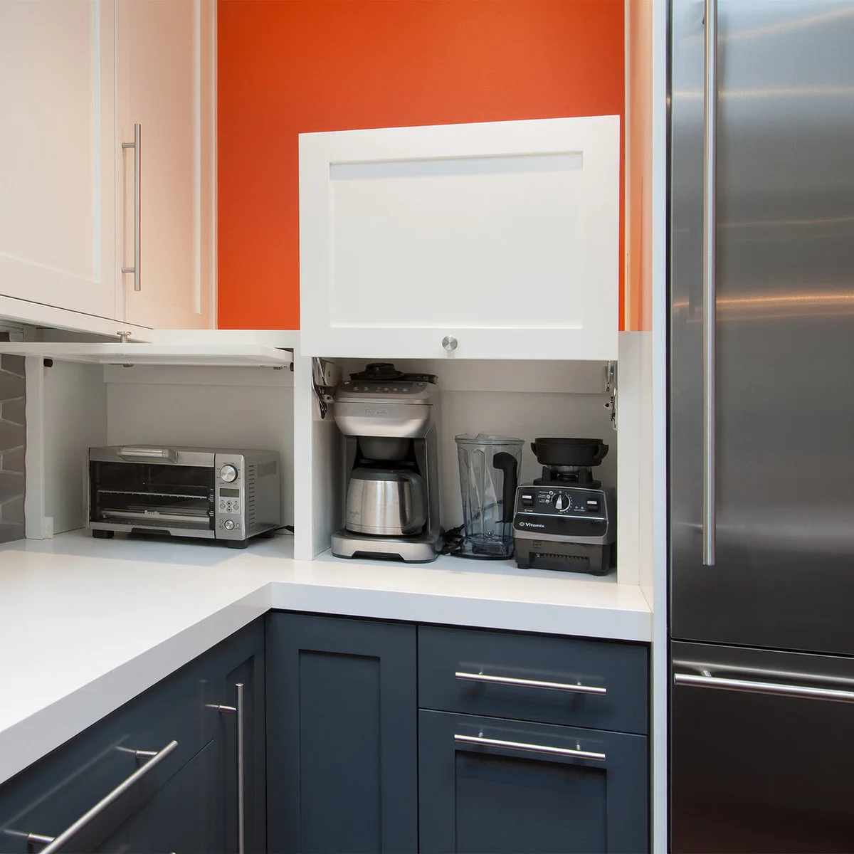 White lift-up cupboard with coffee maker and blender beside a corner countertop