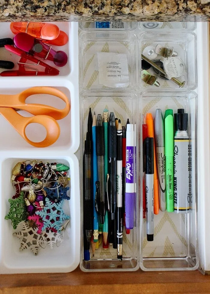 Clear trays beside a white drawer insert holding pencils, markers, keys and small fasteners