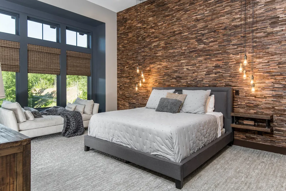A textured stone wall rises behind a pale bed beside tall dark-framed windows