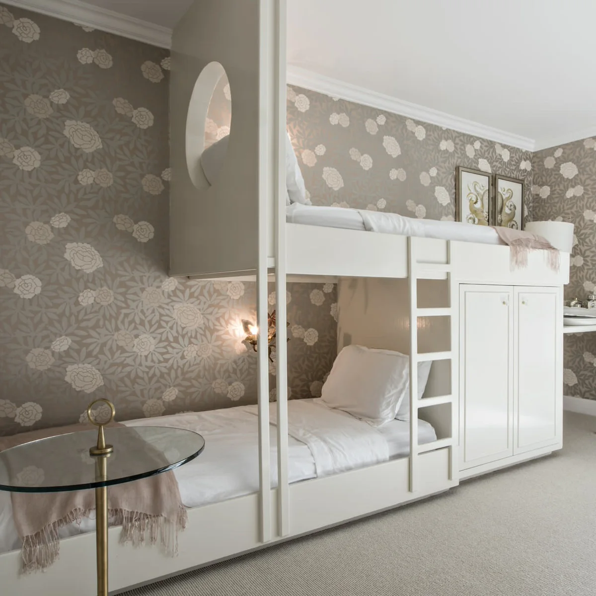 Grey floral wallpaper around white built-in bunk beds with white bedding