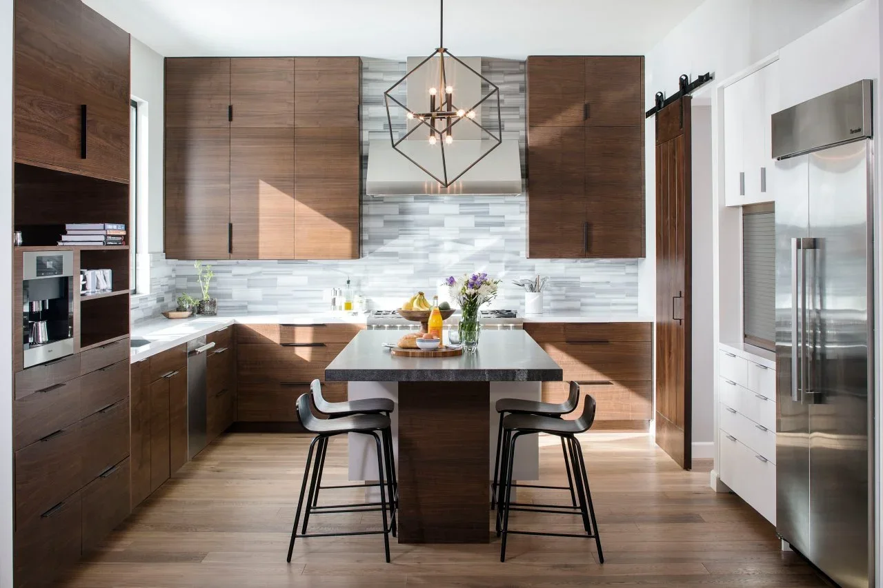 Walnut cupboards surround a dark-topped island, while white cabinets frame the refrigerator and gray patterned tile backs the range.