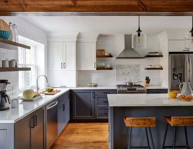Dark blue lower cabinets sit below white uppers and an exposed timber beam.