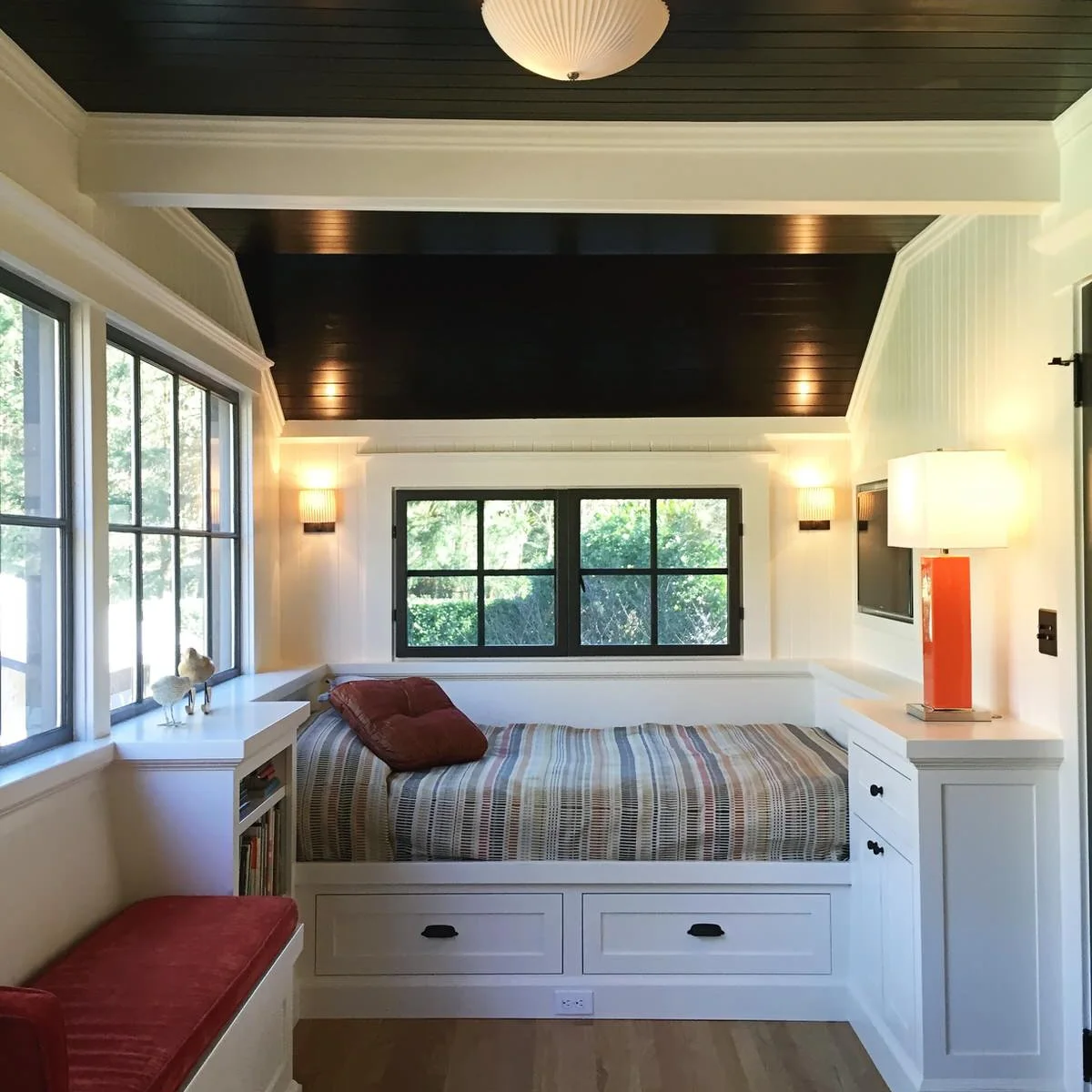 Narrow bedroom nook with a single bed, drawers underneath, white bedside storage and dark boarded ceiling