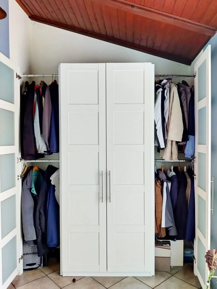 Hallway storage with a central white PAX cabinet and open side sections containing coats on two rails