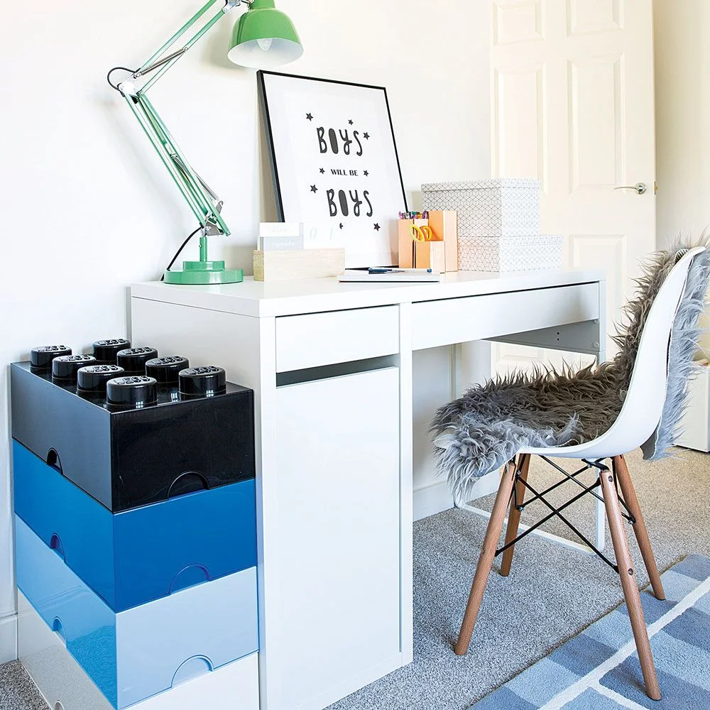 White child-size desk beside a stack of blue and black building-block-shaped storage boxes