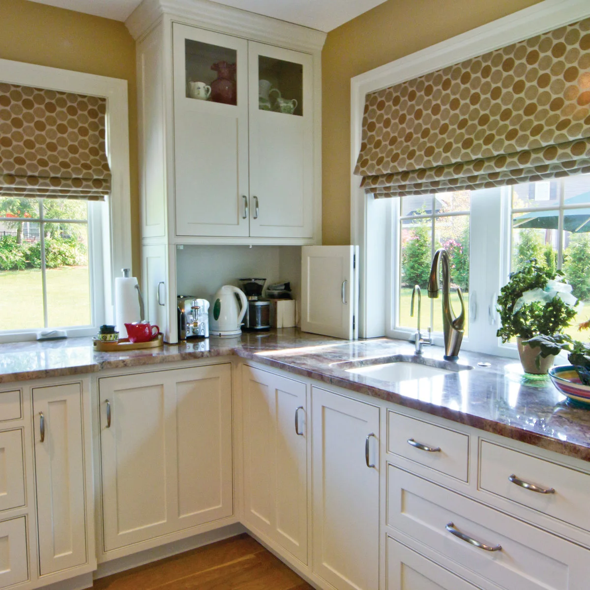 Tall white corner cupboard between kitchen windows with an open appliance compartment