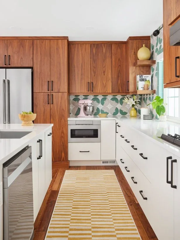 Walnut upper cupboards and a tall refrigerator surround meet white drawers, a built-in microwave and green patterned tile.
