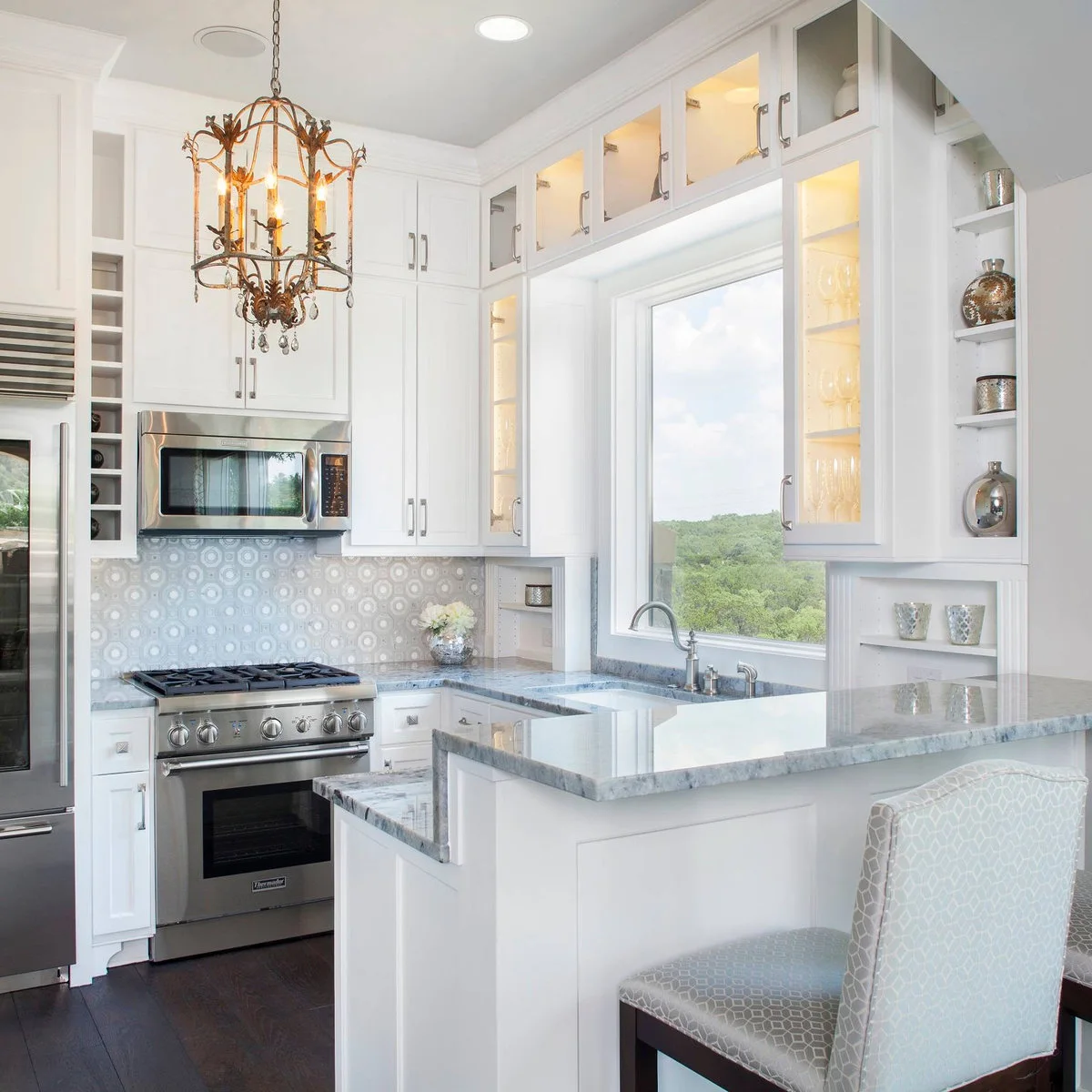 Small white kitchen with illuminated glass cabinets framing a large sink window