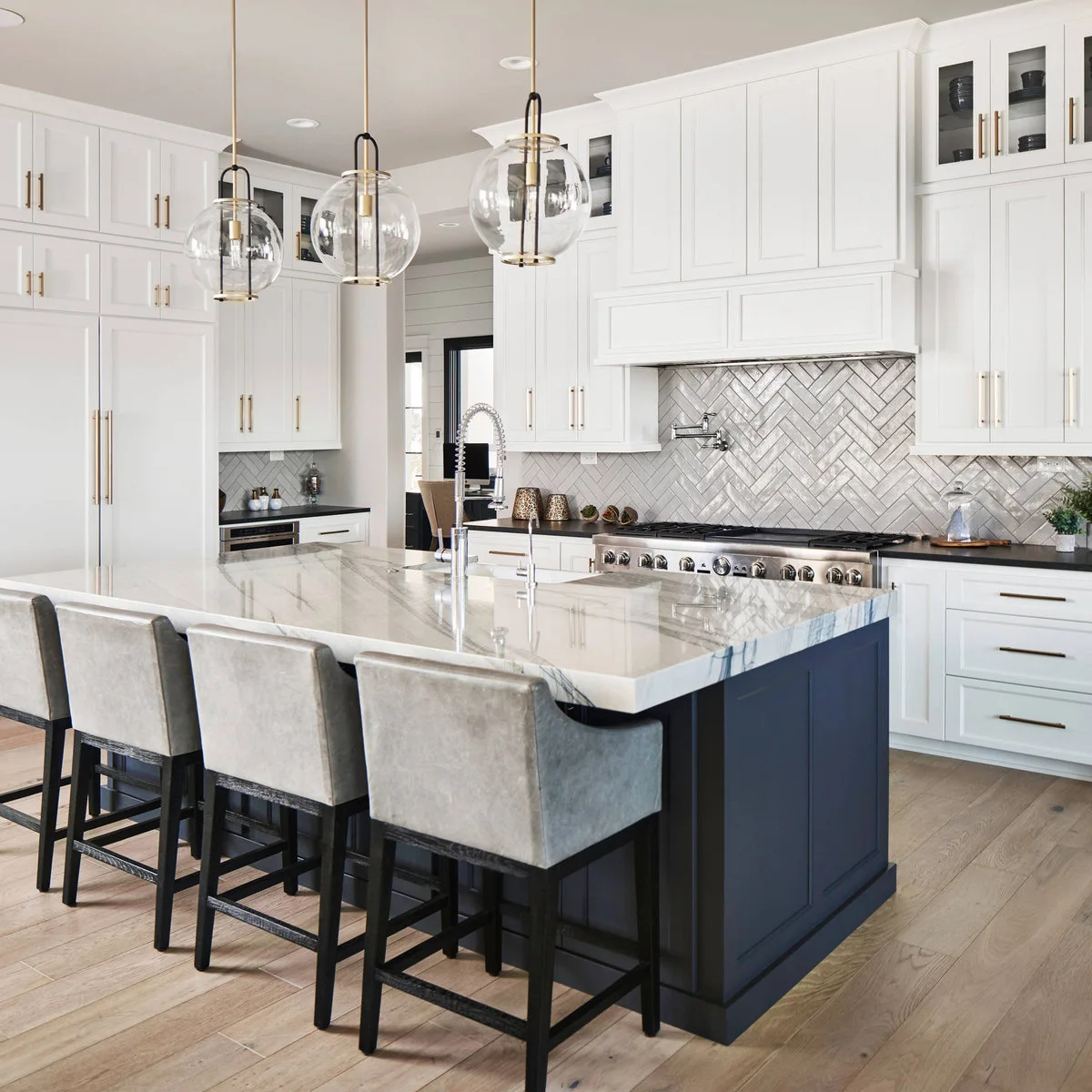 Dark blue island beneath a pale veined counter in a white kitchen