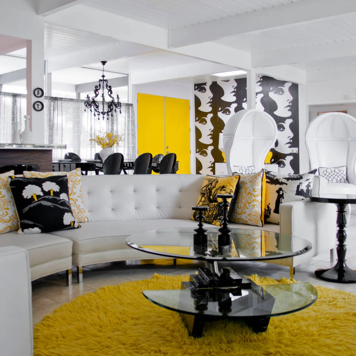 Black-and-white living room with a bright yellow rug, yellow cushions and yellow doors visible behind the seating