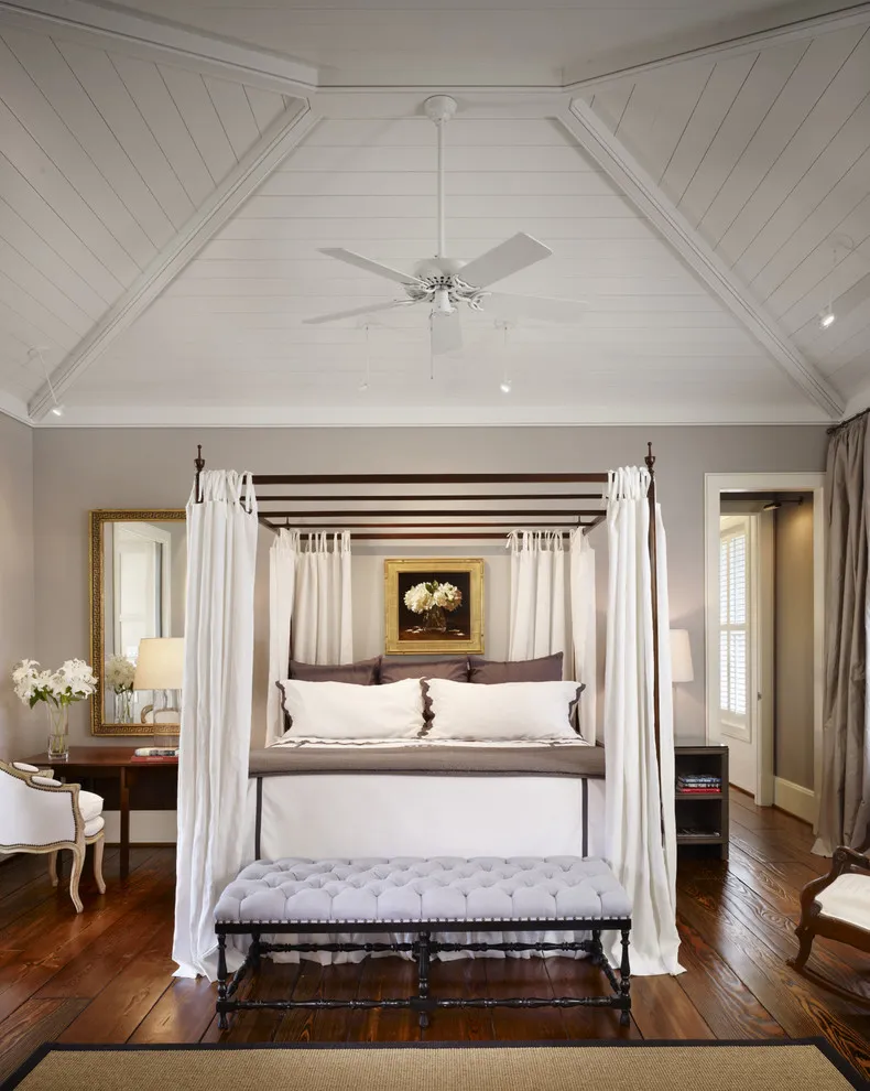 Pale tufted bench with dark decorative stretchers in front of a curtained canopy bed