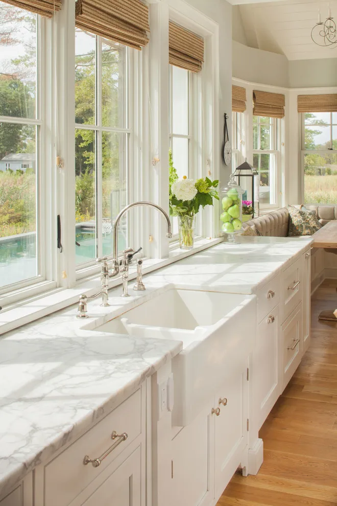 Light cream lower cabinets extend beneath several bright windows and pale counters