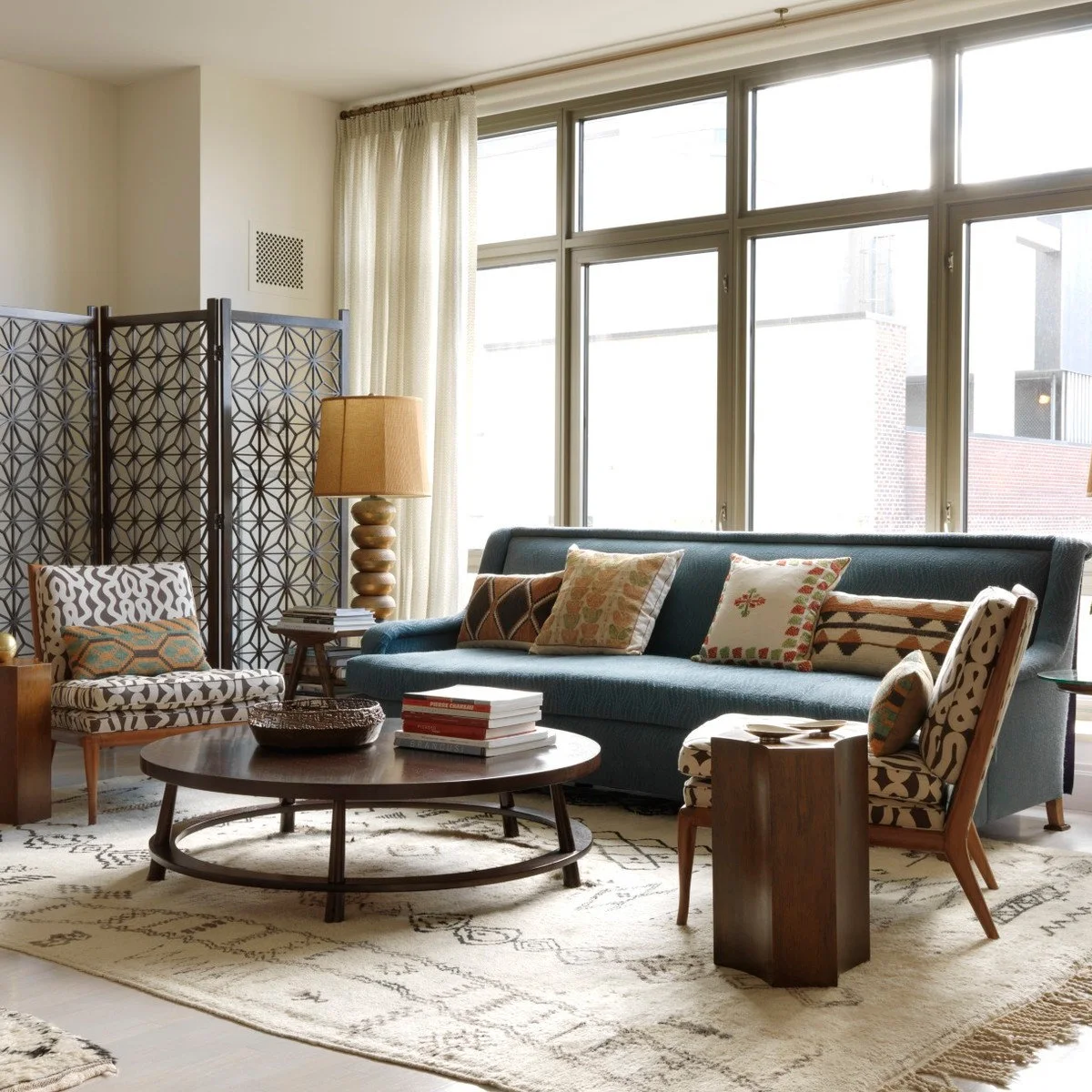 Round dark coffee table with a woven bowl and book stack in front of a blue sofa