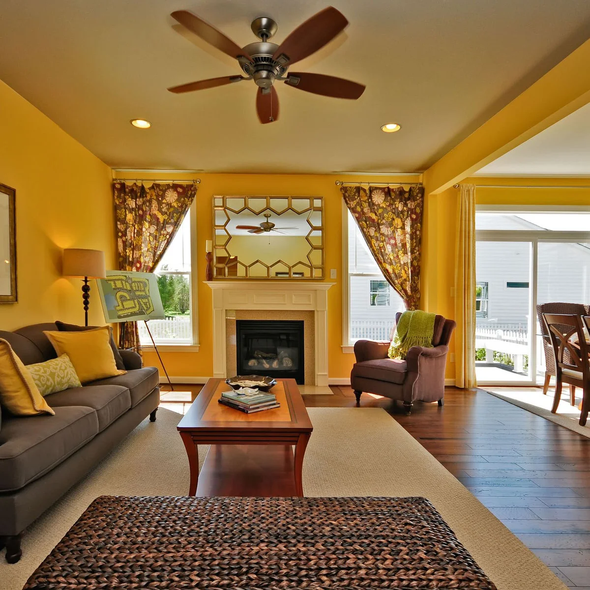 Charcoal sofa with yellow cushions in a living room with golden yellow walls and dark wood flooring.