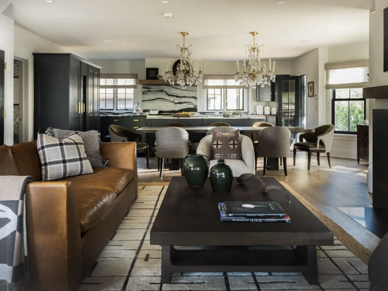 A tan sofa and dark coffee table face an open kitchen with a dining table between the two areas.