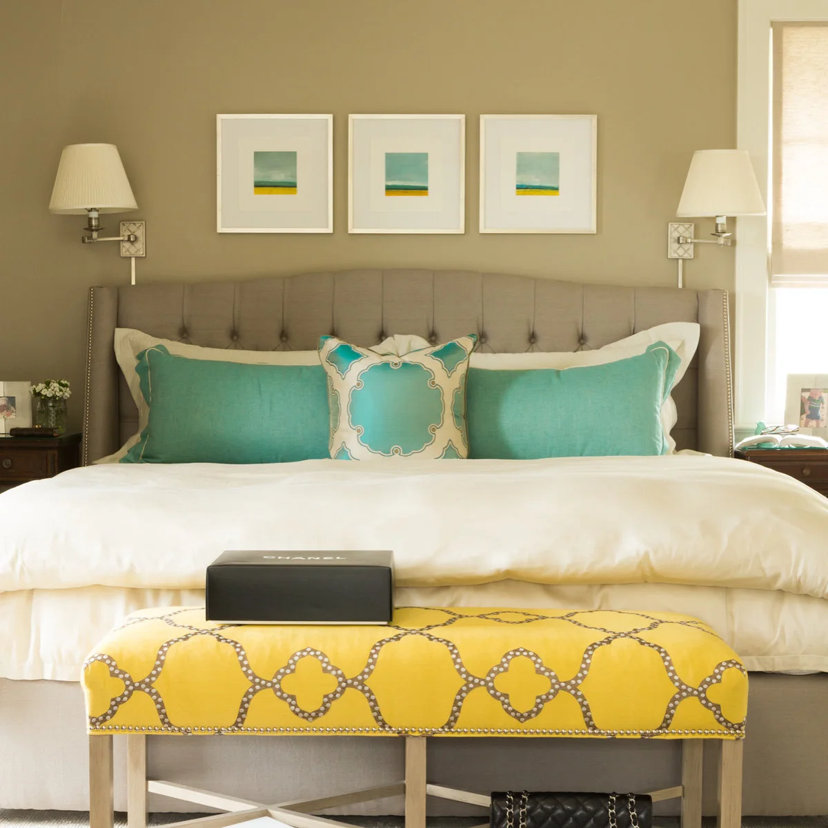 Yellow patterned bench with pale wooden legs in a bedroom with turquoise cushions