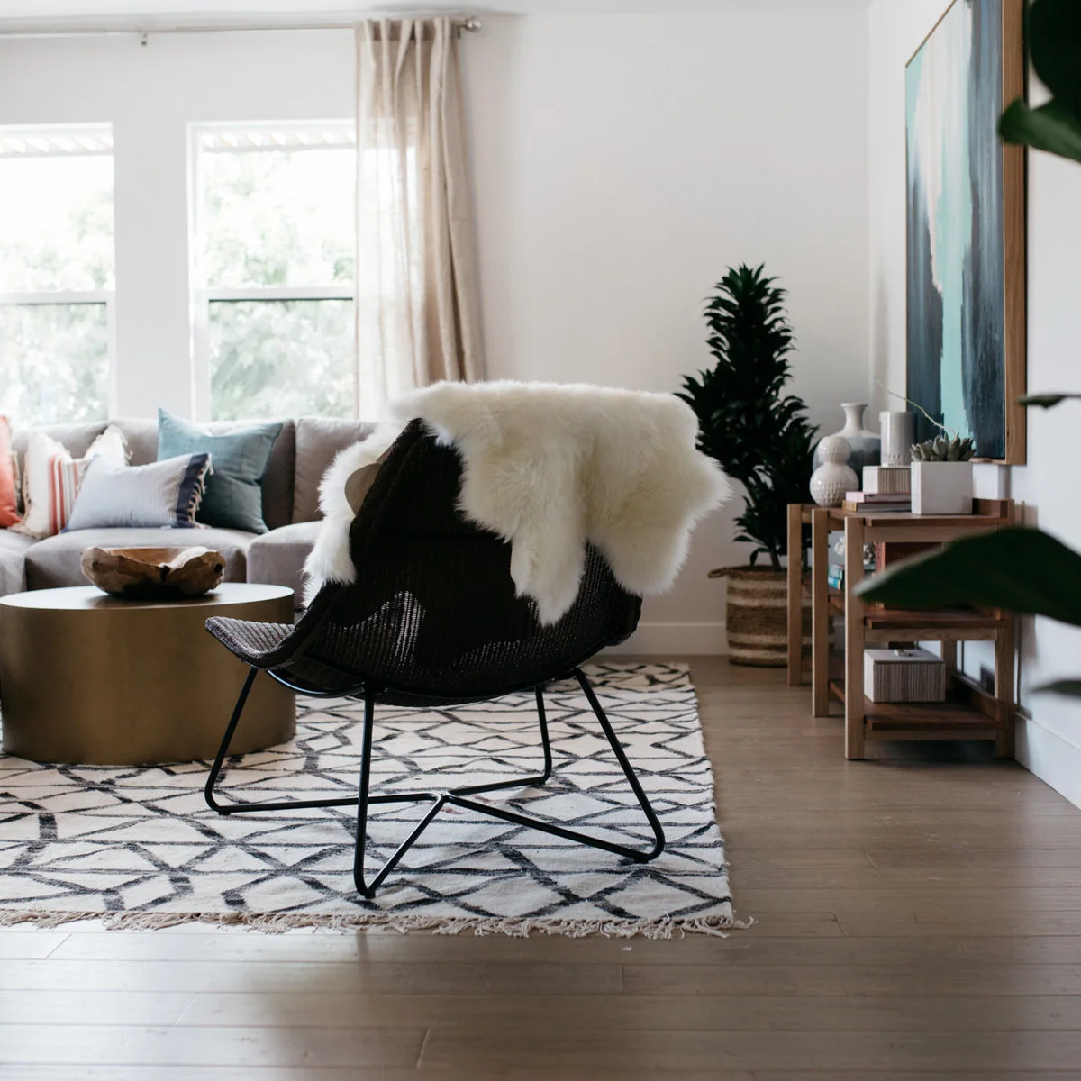 White-walled living area with a black open-framed chair, pale throw and patterned rug