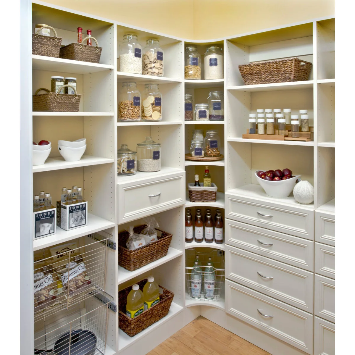 White pantry with a stepped spice rack, labeled jars and lower drawers