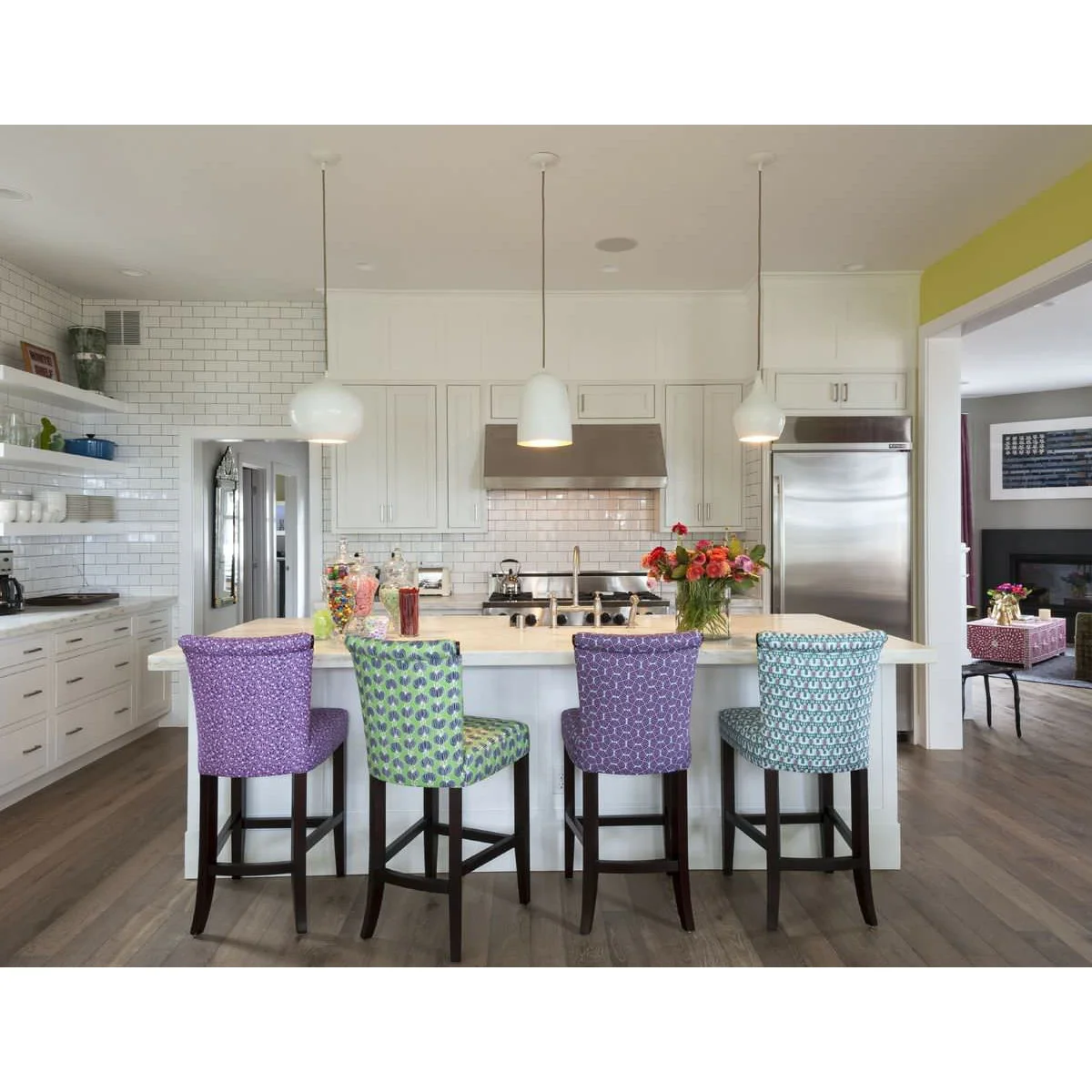 Four kitchen stools with different purple, green and blue patterned fabrics on matching dark legs