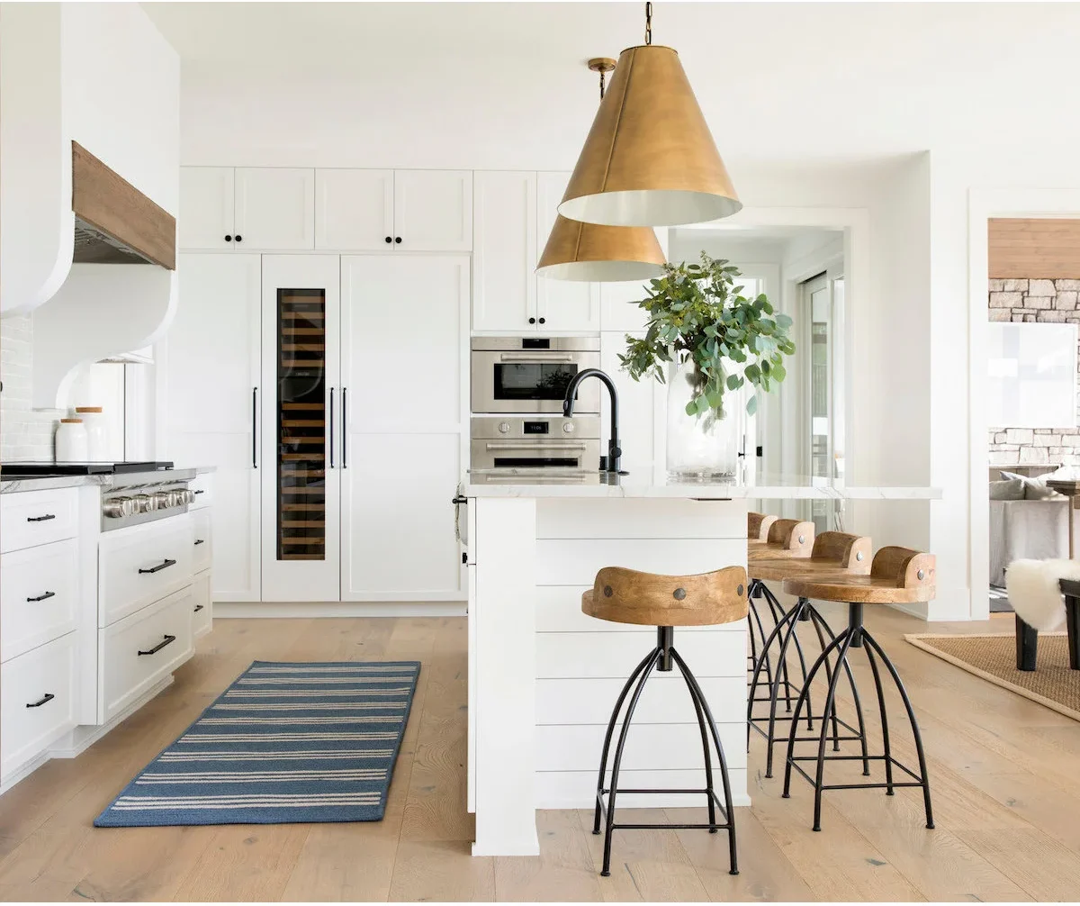 White upper cupboards continue across a paneled appliance wall with a narrow glass-front wine unit.