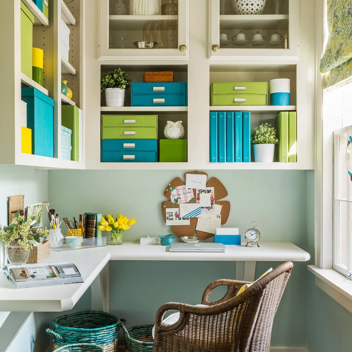 Corner office with white shelves, turquoise and lime storage boxes, pale mint wall and woven chair