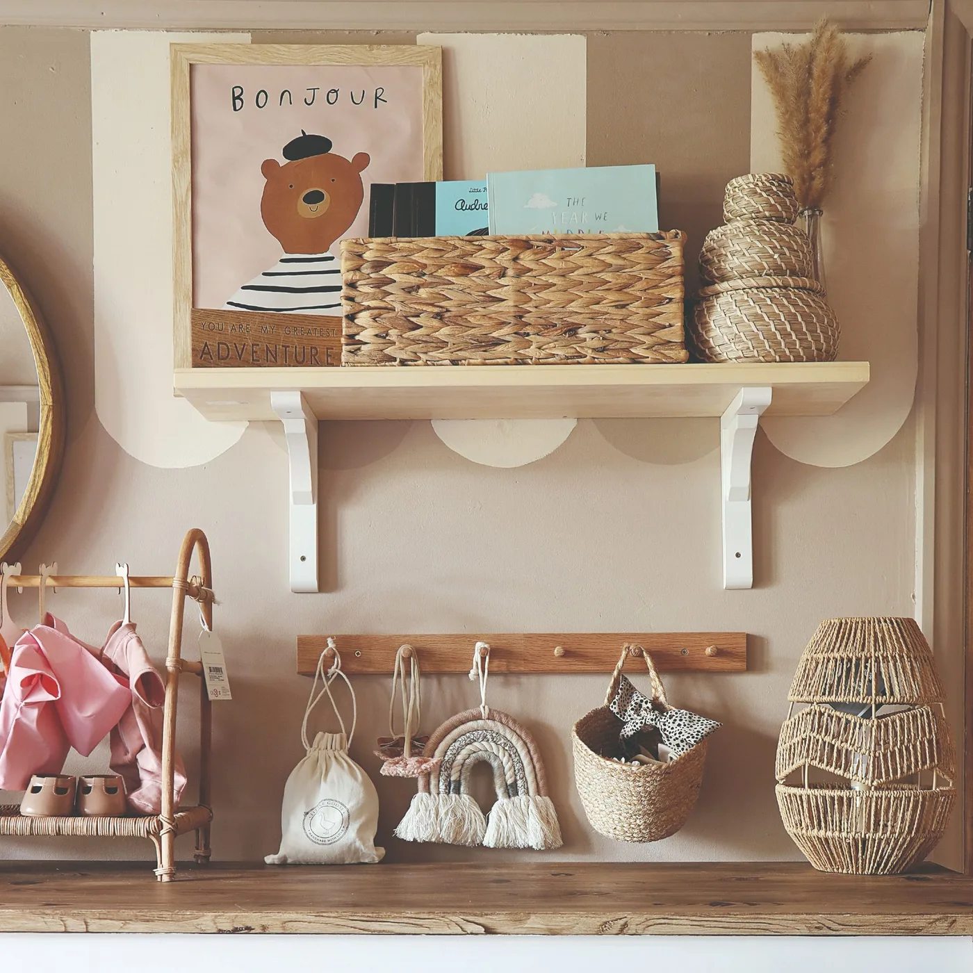A narrow shelf and wooden peg rail hold baskets, books and small objects against a pale nursery wall