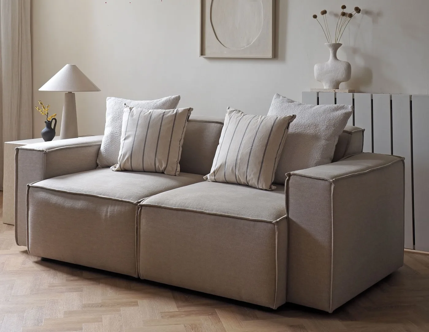 The same pale sofa with square striped and textured white pillows arranged at both ends.