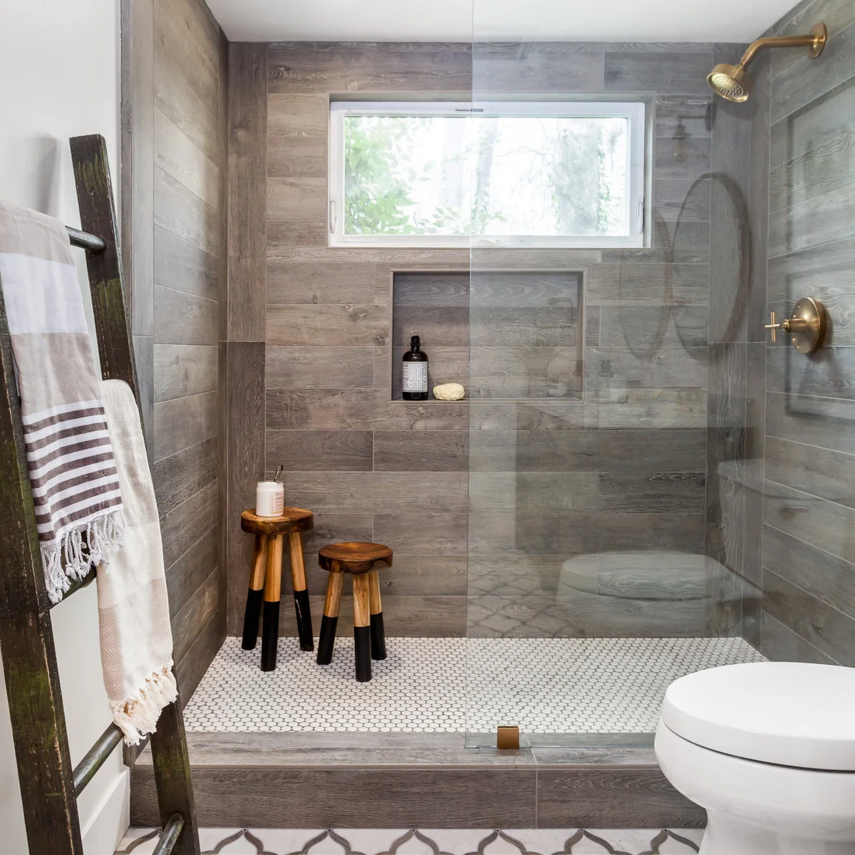 Bathroom shower with grey wood-grain wall tiles, a large niche and two small wood stools