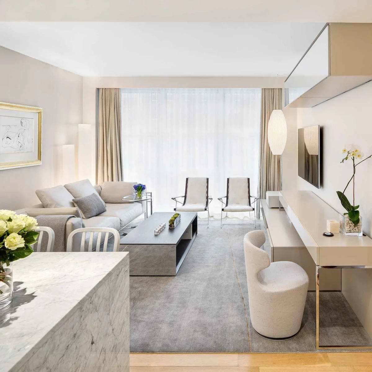 A pale long console runs beneath a television and holds a white orchid, with a curved upholstered seat at one end.