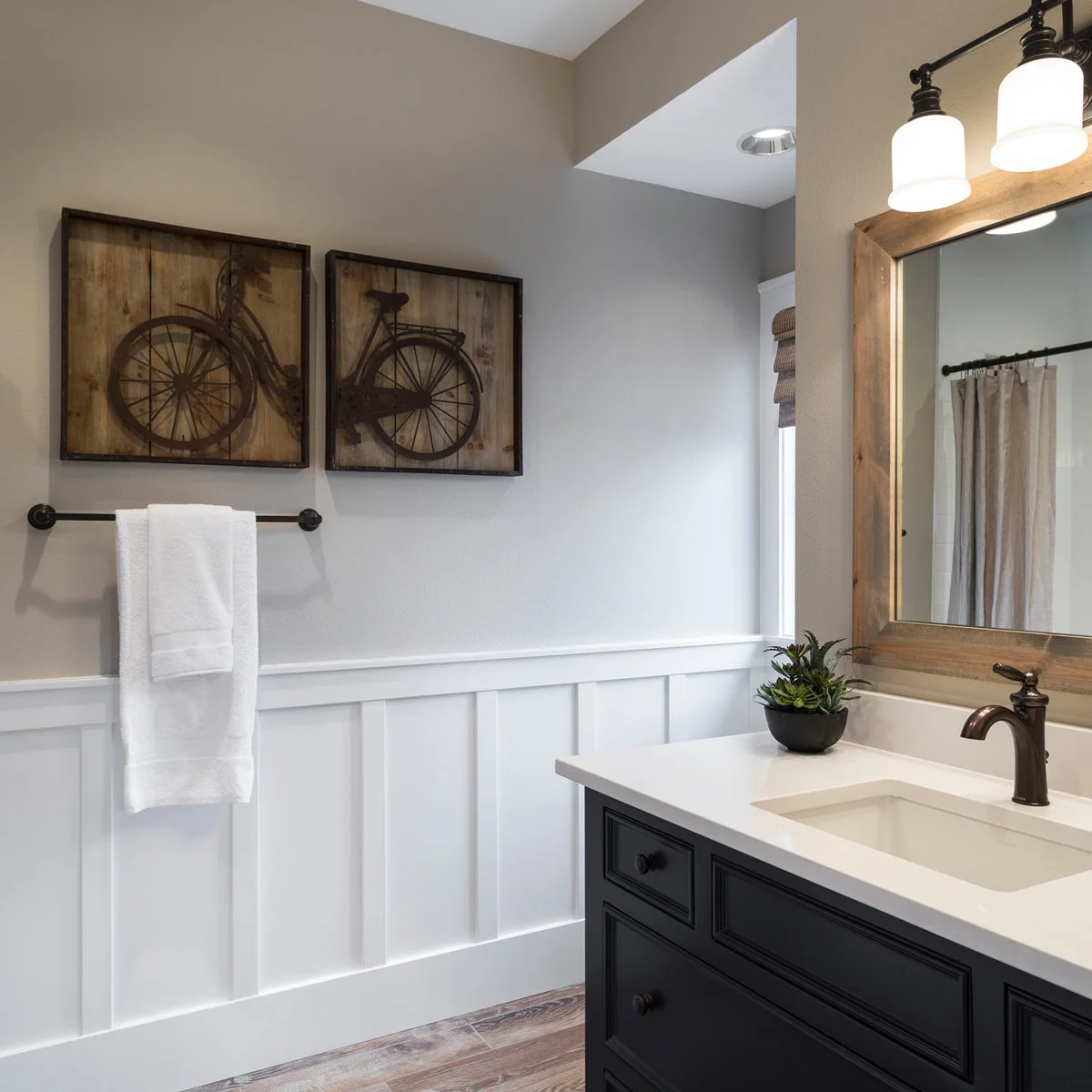 Two bicycle pictures above a towel rail beside a wood-framed bathroom mirror