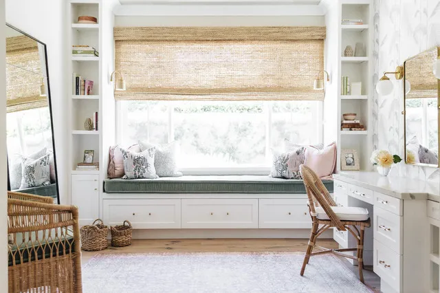 A pale window bench sits between shelving and a small work surface with a timber chair.